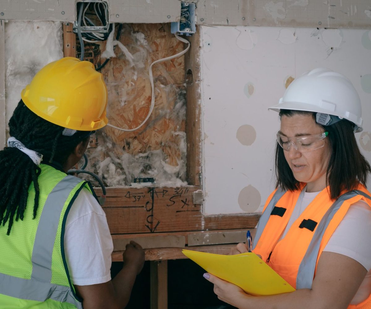 Real photograph of inspectors with clipboard examining home wall systems for home inspections Crown Point shop